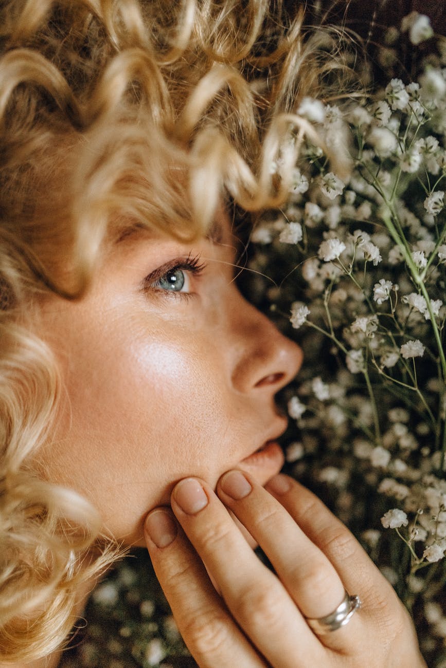 close up photo of woman s face near white flowers